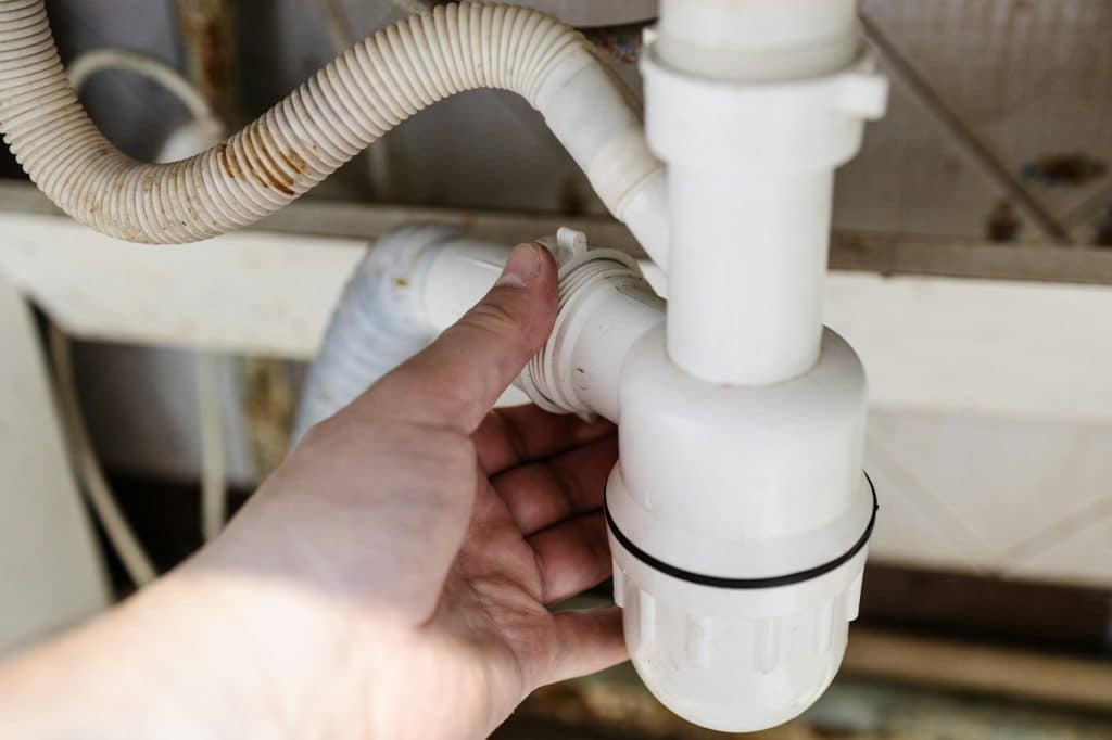 Trusted Sewer Line Cleaning, Repair, and Replacement in Northeast Indiana | plumber disassembles an siphon close up in kitchen