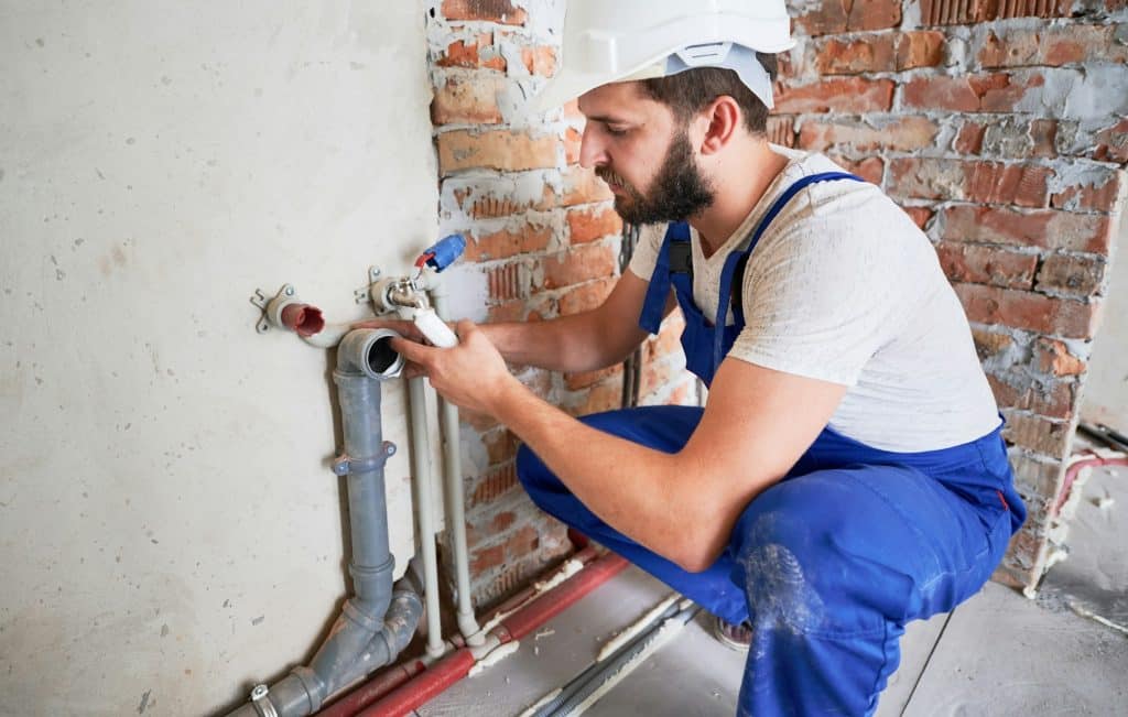 Expert Sewer Line Cleaning, Repair, and Replacement in Northeast Indiana | Young plumber working with sealant fix of sewer pipe